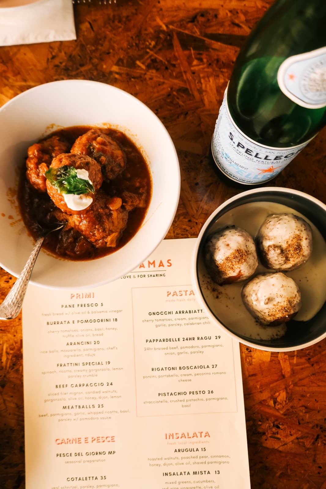 A spread at Mamasamas — meatballs, menu, and S.Pellegrino on the table